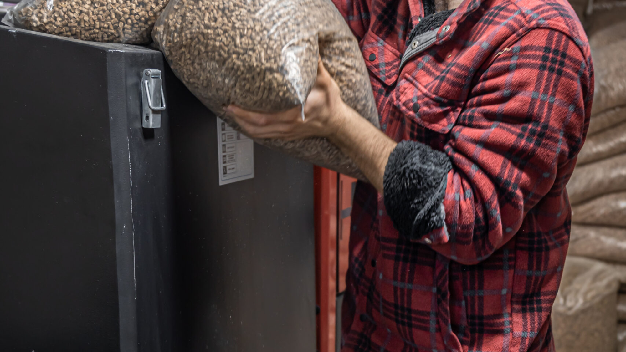The man loads the pellets in the solid fuel boiler, working with biofuels, economical heating.
