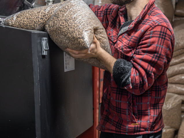 The man loads the pellets in the solid fuel boiler, working with biofuels, economical heating.