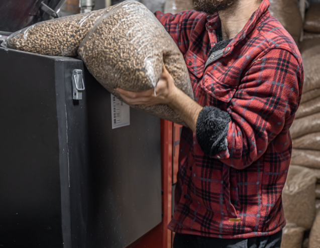 The man loads the pellets in the solid fuel boiler, working with biofuels, economical heating.